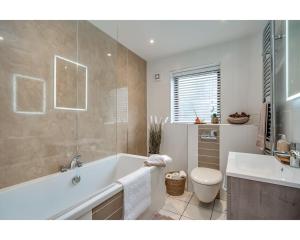 a bathroom with a tub and a toilet and a sink at Central Belfast Apartments Windsor in Belfast