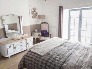 a bedroom with a bed and a mirror and a chair at La ferme de la Chapelle - Gîte et chambres d'hôtes in Cherain