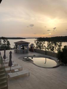 einen Pool mit Stühlen, einem Pavillon und Wasser in der Unterkunft Casa Rural encantos de Orellana in Navalvillar de Pela