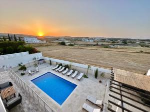 a pool on a patio with chairs and a sunset at Amazing Luxury Villa Larnaca in Aradhippou