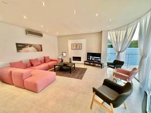 Aradhippou的住宿－Amazing Luxury Villa Larnaca，大型客厅配有粉红色的沙发和椅子