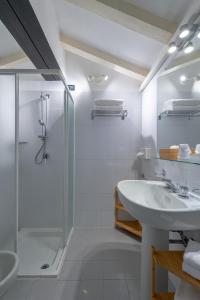 La salle de bains blanche est pourvue d'une douche et d'un lavabo. dans l'établissement Residenza Accademia, à Mantoue