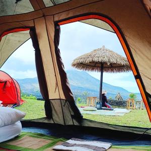 una persona seduta all'interno di una tenda con vista di Kintamani Adventure Hidden Lodge a Kintamani