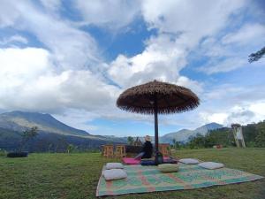 uma pessoa sentada num cobertor debaixo de um guarda-chuva em Kintamani Adventure Hidden Lodge em Kintamani