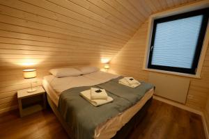 een slaapkamer met een bed in een houten kamer met een raam bij Solano Apartments in Stepnica