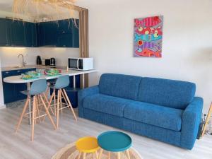 uma sala de estar com um sofá azul e uma mesa em Au Ti Menhir * 2 à 4 vacanciers * Piscine * WIFI em Carnac
