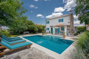 eine Villa mit einem Pool und einem Haus in der Unterkunft Heritage Villa Laurel in Malinska