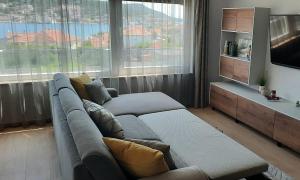 - un salon avec un canapé et une grande fenêtre dans l'établissement Villa Kapetanova Lanterna luxury apartment Barka with heated pool, à Vinišće