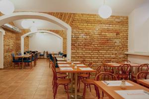 een eetkamer met tafels en stoelen en een bakstenen muur bij Hotel Ambiance in Praag