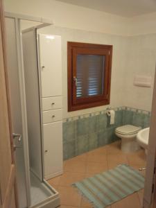 ein Bad mit einem WC und einem Fenster in der Unterkunft Dimora San Pietro in Budoni