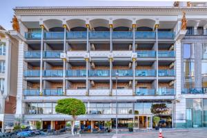 un edificio de apartamentos con balcones y un árbol delante de él en Numa Port Hotel en Alanya