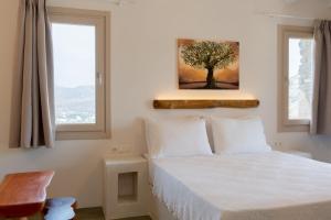 1 dormitorio con 1 cama con una pintura de árbol en la pared en Heliopetra Punta, en Ios Chora