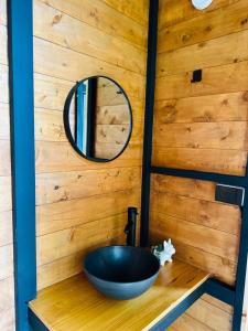 a bathroom with a sink and a mirror on a wooden wall at Rainbow Glamping in Abejorral