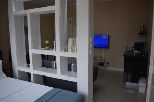 a room with a bed and a desk and a television at Cozy Studio in Luanda