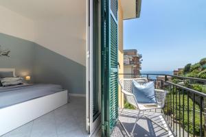 a bedroom with a bed and chairs on a balcony at La Casa di Madi in Riomaggiore