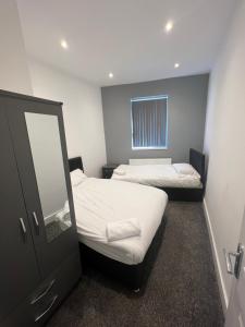 a small room with two beds and a mirror at City West Apartments 3 bedroom large & modern Apartment in Newcastle upon Tyne