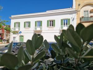 een wit gebouw met groene ramen aan een straat bij Vaaz Rooms in Sannicandro di Bari