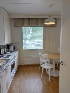 a kitchen with white cabinets and a table and a window at Asuntos-2 in Lahti