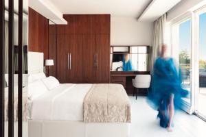 a woman in a blue dress walking through a bedroom at Lusso Mare Istria Luxury Beach villa in Savudrija