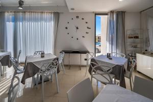 a dining room with two tables and a clock on the wall at Villa Floyd Charming Rooms B&B in Pachino