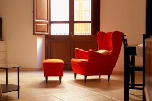 a living room with a red chair and a stool at Sardinian Gallery Corso in Bosa