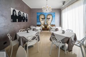 a restaurant with white tables and a painting of two faces at Villa Floyd Charming Rooms B&B in Pachino