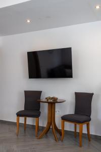 2 sillas y mesa con TV en la pared en Alex Luxury Downtown House, en Naxos Chora