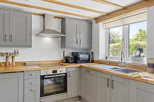 cocina con armarios blancos, fregadero y ventana en Luxurious Barn Conversion en Oakamoor