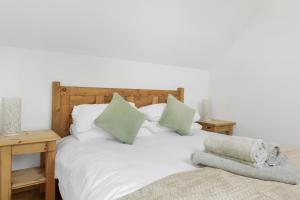 a bedroom with a white bed with green pillows at Luxurious Barn Conversion in Oakamoor