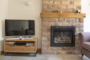 a living room with a brick fireplace and a television at Luxurious Barn Conversion in Oakamoor