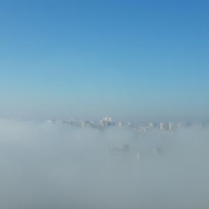 un lago nublado con una ciudad en el fondo en VApartments en Kiev