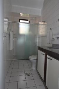 a white bathroom with a toilet and a shower at Flat Itararé Tower Beach in São Vicente