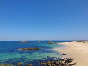 a sandy beach with rocks in the water at Hôtel Ker-Noyal Quiberon Plage in Quiberon