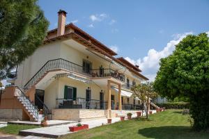 a large white house with a porch and stairs at Olivemare Holidays in Nea Irakleia