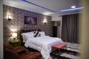 a bedroom with a large bed and a brick wall at Brynx Haven - Adenta, Accra in Accra