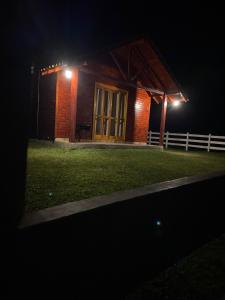 a small brick building with a porch at night at Cabana Furna dos Pôneis in Urubici
