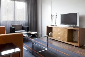 a living room with a television on a wooden entertainment center at Hotel Palau de Bellavista Girona by URH in Girona +13 photos