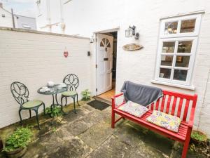 un banco rojo, dos sillas y una mesa en The Cottage en Stratford-upon-Avon