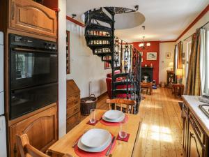 a kitchen with a dining table and a spiral staircase at The Cottage in Stratford-upon-Avon
