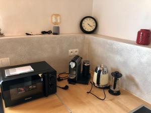 a counter with a microwave and a clock on a wall at Domček pod Orechom in Blatnica
