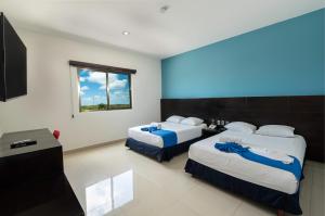 a hotel room with two beds and a television at Hotel Ambra in Playa del Carmen