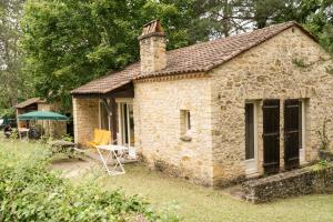 a small stone house with a table and a green umbrella at Les gites de Sarlat in Sarlat-la-Canéda