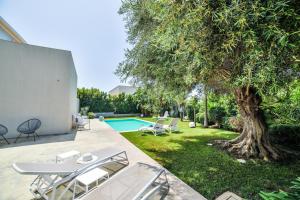 een achtertuin met een boom en een zwembad bij Villa Ponente - Design House with Private Pool in Marina di Ragusa