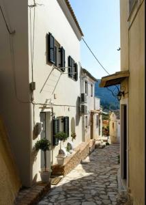 a narrow alley with white buildings and potted plants at The Gastouri House, Located In Central Corfu, Near Benitses in Gastouri