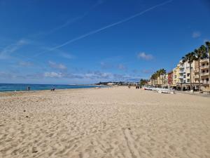 a beach with people and buildings and the ocean at Apartamentos Wundermar in Torredembarra