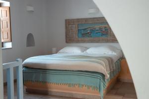 a bedroom with a bed with a painting on the wall at XARAKI Traditional Houses in Chora Folegandros