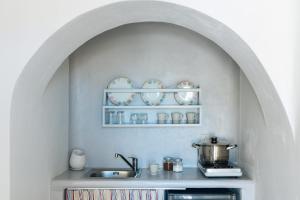 a kitchen with a sink and a shelf with dishes at XARAKI Traditional Houses in Chora Folegandros