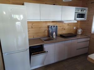 a kitchen with white cabinets and a white refrigerator at 4 Domki u Ewy in Ryn