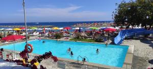 ein Schwimmbecken mit Menschen im Wasser und Sonnenschirmen in der Unterkunft PAMA MAR in Imperia