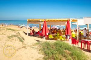 a group of people sitting at a restaurant on the beach at Lighthouse Parquemar in La Mata